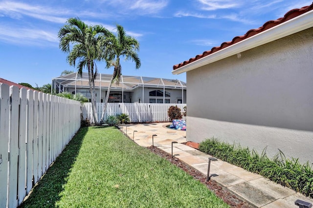 view of yard with glass enclosure, a fenced backyard, and a patio area