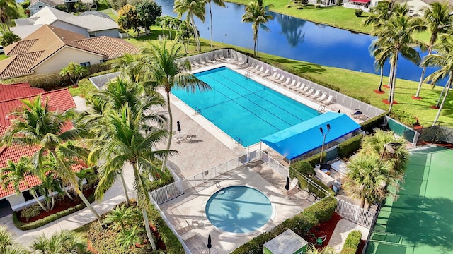 pool with fence, a water view, and a yard