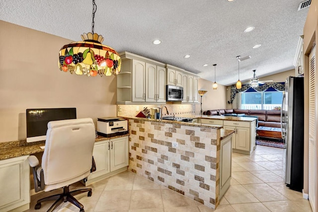 kitchen featuring a peninsula, cream cabinetry, and stainless steel appliances