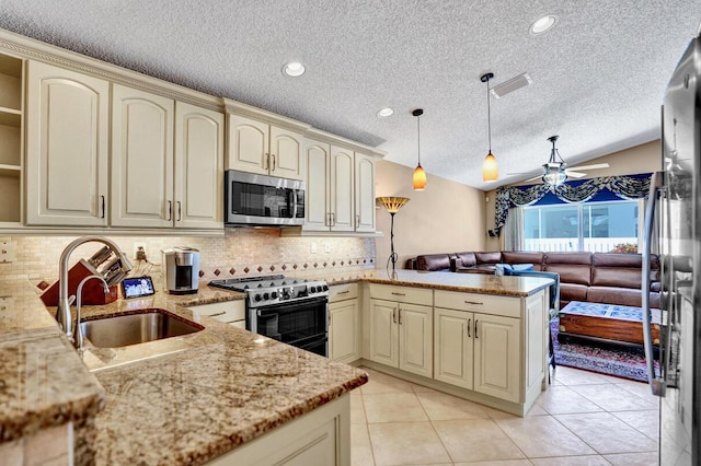 kitchen featuring a peninsula, ceiling fan, cream cabinets, a sink, and appliances with stainless steel finishes