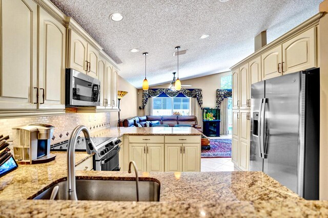 kitchen featuring a textured ceiling, appliances with stainless steel finishes, decorative backsplash, and cream cabinetry