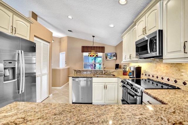 kitchen with a peninsula, a sink, backsplash, vaulted ceiling, and stainless steel appliances