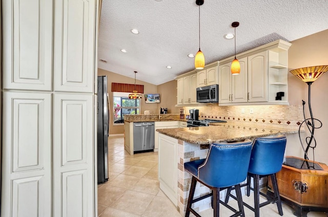 kitchen featuring a peninsula, lofted ceiling, tasteful backsplash, appliances with stainless steel finishes, and light tile patterned floors