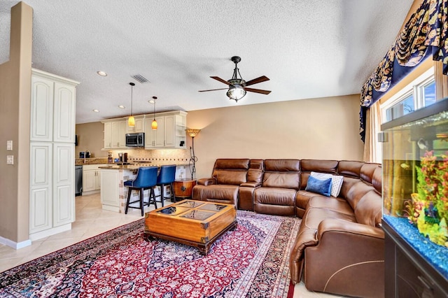 living area with ceiling fan, a textured ceiling, baseboards, recessed lighting, and light tile patterned flooring