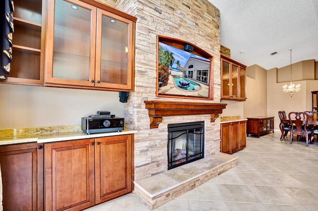 kitchen featuring light tile patterned flooring, an inviting chandelier, a fireplace, brown cabinetry, and vaulted ceiling