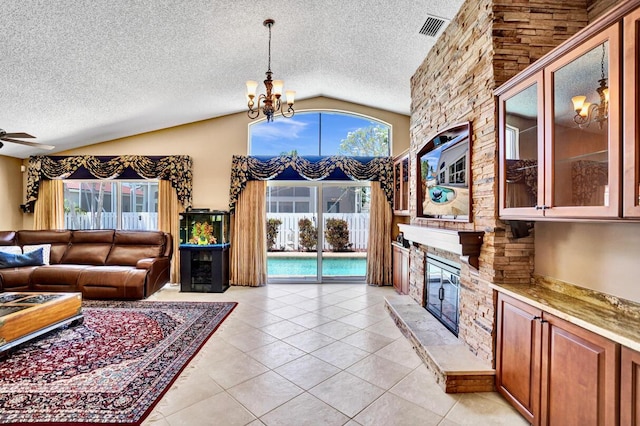 living area with a textured ceiling, a stone fireplace, and visible vents