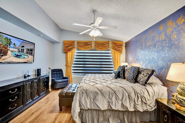 bedroom with a textured ceiling, ceiling fan, light wood-style flooring, and lofted ceiling