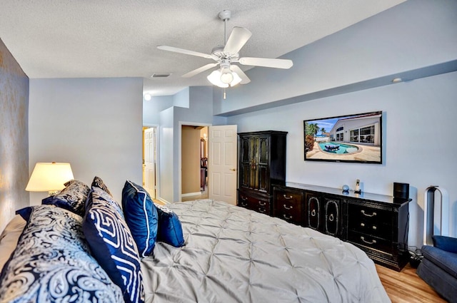 bedroom with a textured ceiling, ceiling fan, wood finished floors, and visible vents