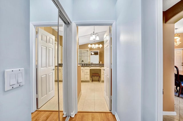 corridor featuring light wood-type flooring and a notable chandelier