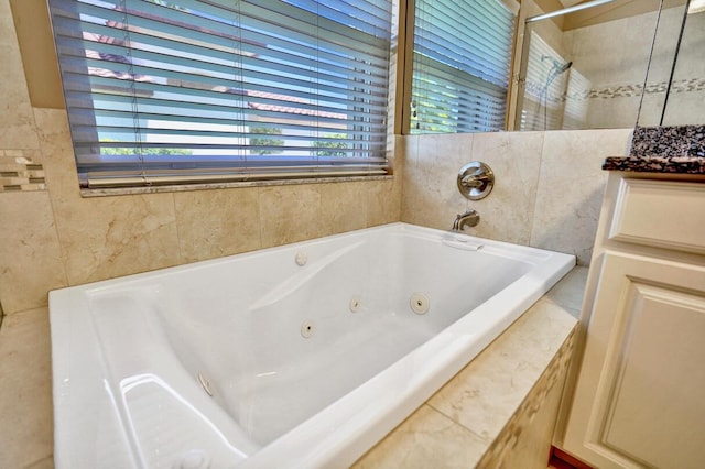 full bathroom featuring tile walls, a tub with jets, a shower, and vanity