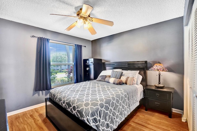 bedroom featuring baseboards, a ceiling fan, a textured ceiling, and wood finished floors