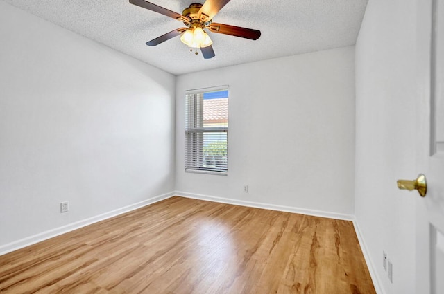 spare room featuring light wood-type flooring, a ceiling fan, a textured ceiling, and baseboards