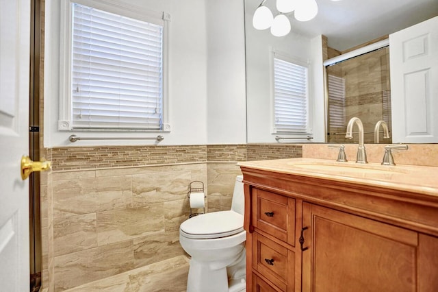full bathroom featuring vanity, toilet, tile walls, a wainscoted wall, and a stall shower