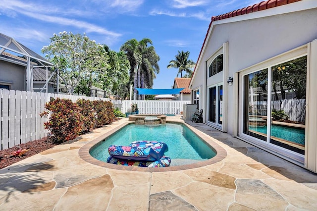 view of swimming pool featuring a pool with connected hot tub, a fenced backyard, and a patio area