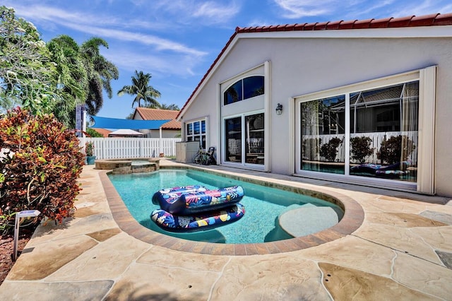 view of swimming pool featuring fence, a pool with connected hot tub, and a patio area