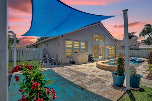 back of house with a pool with connected hot tub, fence, a patio area, and stucco siding