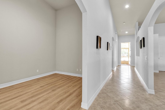 hall with baseboards, recessed lighting, arched walkways, and light tile patterned flooring