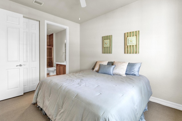 bedroom with ceiling fan, visible vents, baseboards, ensuite bathroom, and light carpet