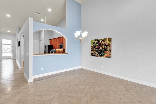 interior space featuring light tile patterned flooring, a notable chandelier, visible vents, and a towering ceiling