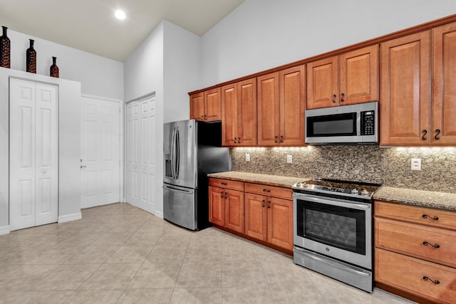 kitchen with stainless steel appliances, light stone countertops, brown cabinetry, and tasteful backsplash