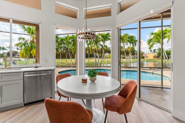 sunroom / solarium featuring a sink, plenty of natural light, and a notable chandelier