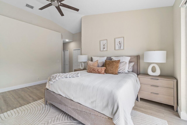 bedroom with light wood-style floors, baseboards, visible vents, and lofted ceiling
