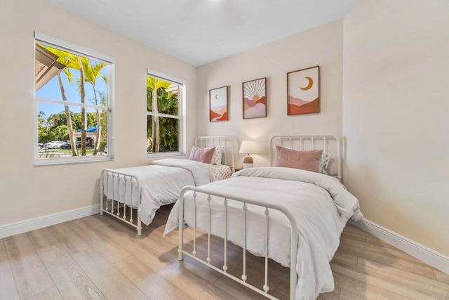 bedroom with baseboards, multiple windows, and wood finished floors