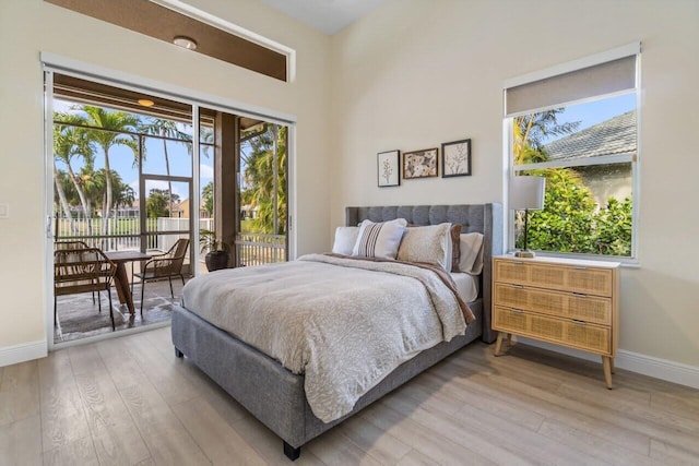 bedroom featuring baseboards, multiple windows, light wood-type flooring, and access to exterior