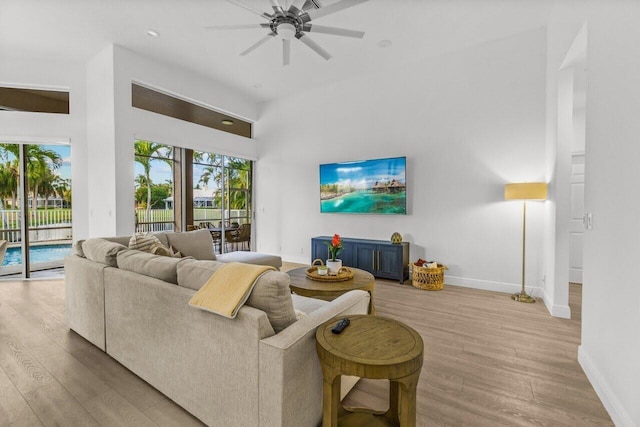 living area featuring baseboards, a ceiling fan, and wood finished floors