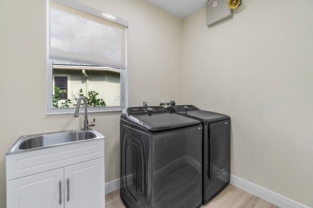 washroom with independent washer and dryer, cabinet space, a sink, baseboards, and light wood-style flooring