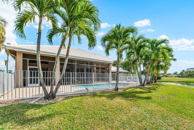 view of swimming pool featuring a sunroom, a lawn, fence, and a fenced in pool