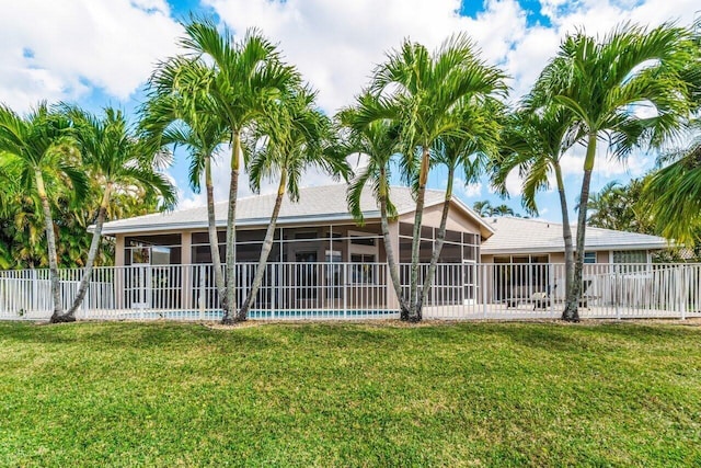 back of property with a lawn, fence, and a sunroom