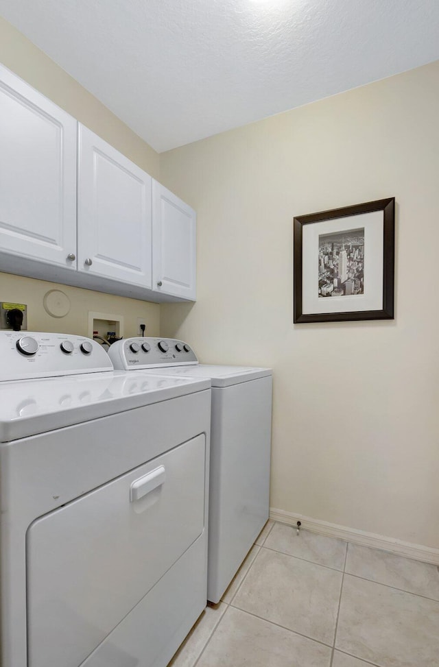 clothes washing area with cabinet space, separate washer and dryer, baseboards, and light tile patterned flooring