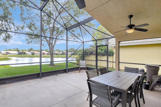 view of patio with a water view, glass enclosure, ceiling fan, and outdoor dining area