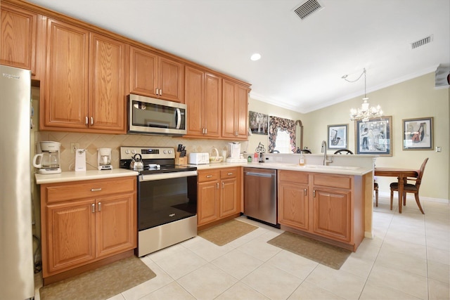 kitchen with stainless steel appliances, a sink, a peninsula, ornamental molding, and a chandelier