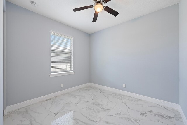 unfurnished room featuring ceiling fan, baseboards, and marble finish floor