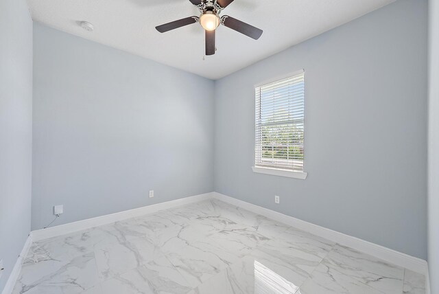 unfurnished room featuring baseboards, marble finish floor, and ceiling fan