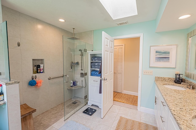 bathroom with a walk in shower, vanity, tile patterned floors, a skylight, and visible vents