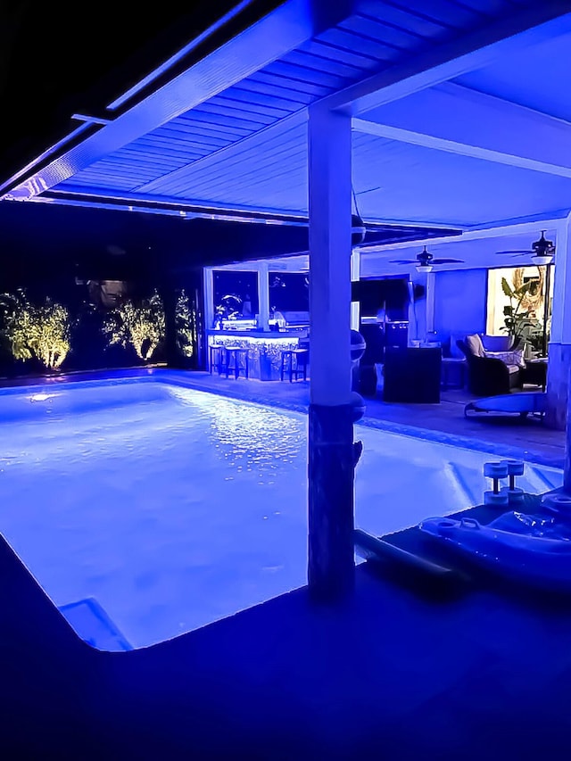 pool at night with a hot tub, a patio, an outdoor pool, and outdoor dry bar