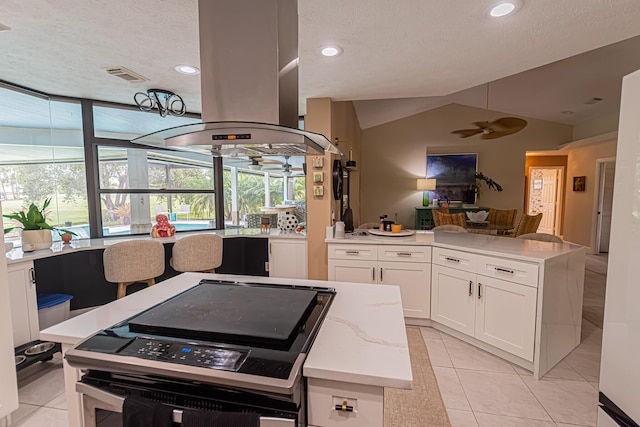 kitchen with ceiling fan, range with electric stovetop, island exhaust hood, visible vents, and vaulted ceiling
