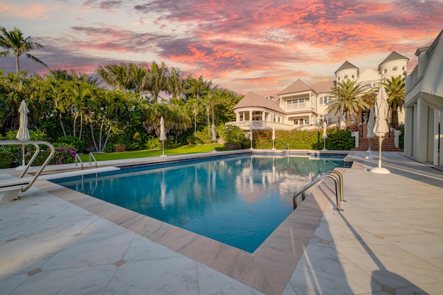 pool at dusk featuring a patio area and an outdoor pool