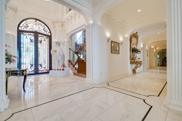 entrance foyer featuring decorative columns, french doors, arched walkways, stairway, and marble finish floor