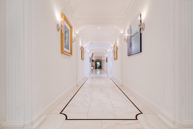 hallway with arched walkways, baseboards, and marble finish floor