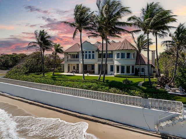 view of front of house with a lawn, a balcony, and a fenced backyard