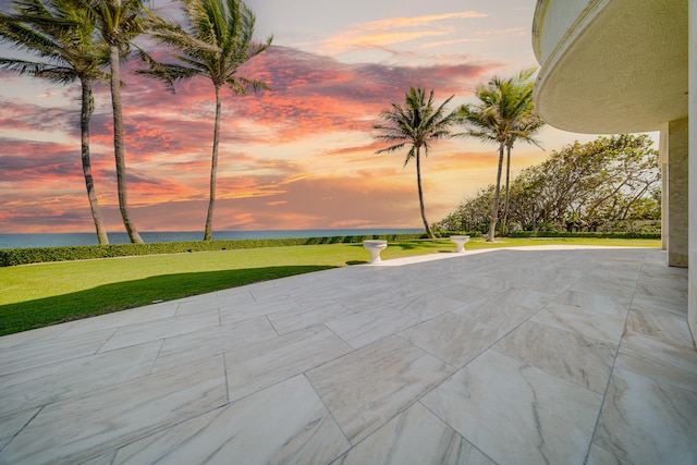patio terrace at dusk with a yard and a water view