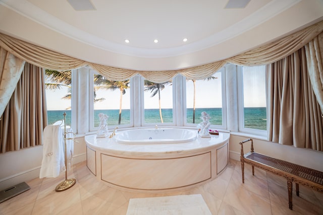 bathroom featuring a water view, baseboards, recessed lighting, and a bath
