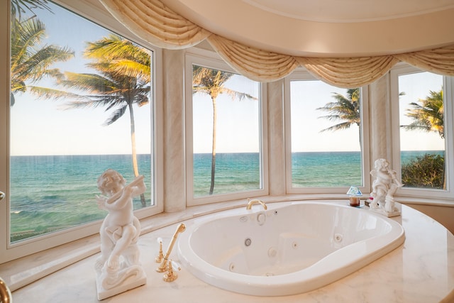 bathroom with a whirlpool tub, a water view, and a wealth of natural light