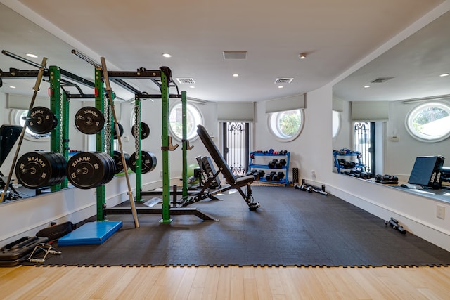 exercise room featuring a healthy amount of sunlight, recessed lighting, wood finished floors, and visible vents