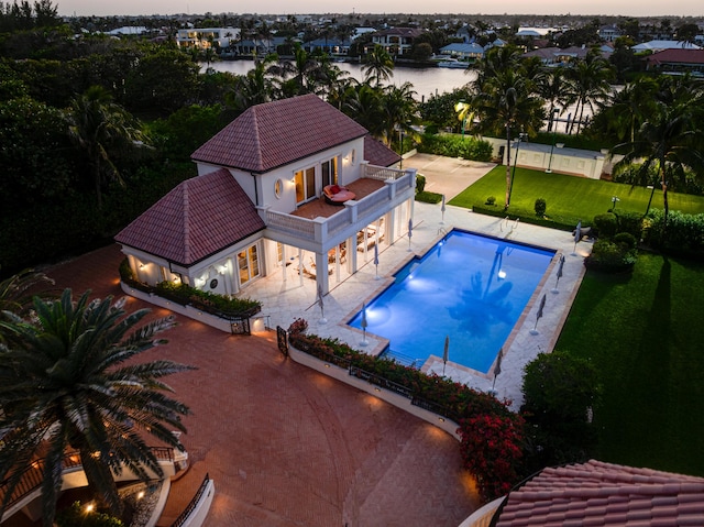 view of pool with fence, a fenced in pool, a water view, a lawn, and a patio