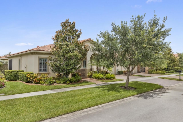 10245 SW Reggiani Rd, Port Saint Lucie, FL 34986 - view of front of house with driveway, a tile roof, a front yard, and stucco siding